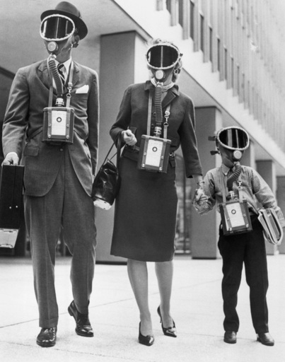 picture of a 1950s era family with dad, mom and son all dressed in their sunday best including gas mask